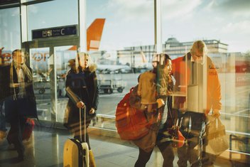 Des voyageurs font la queue avec leurs bagages au niveau d'une porte d'embarquement dans un aéroport.