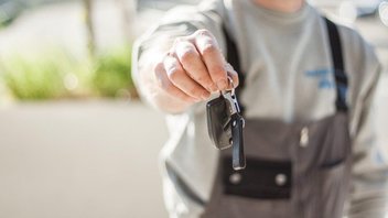 Un mécanicien tend les clés d'un véhicule.