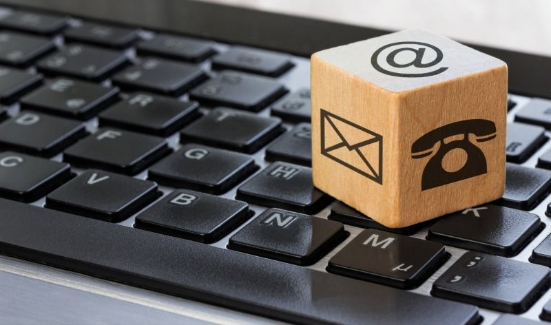 Kontakt-Symbole auf Würfel (@, E-Mail, Telefon) auf einer Computertastatur.