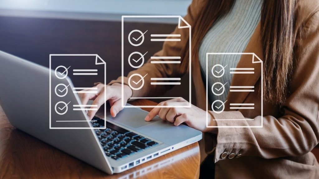 Eine Frau tippt am Laptop. Im Vordergrund sind Vertragsblätter als Icons zu sehen.icons