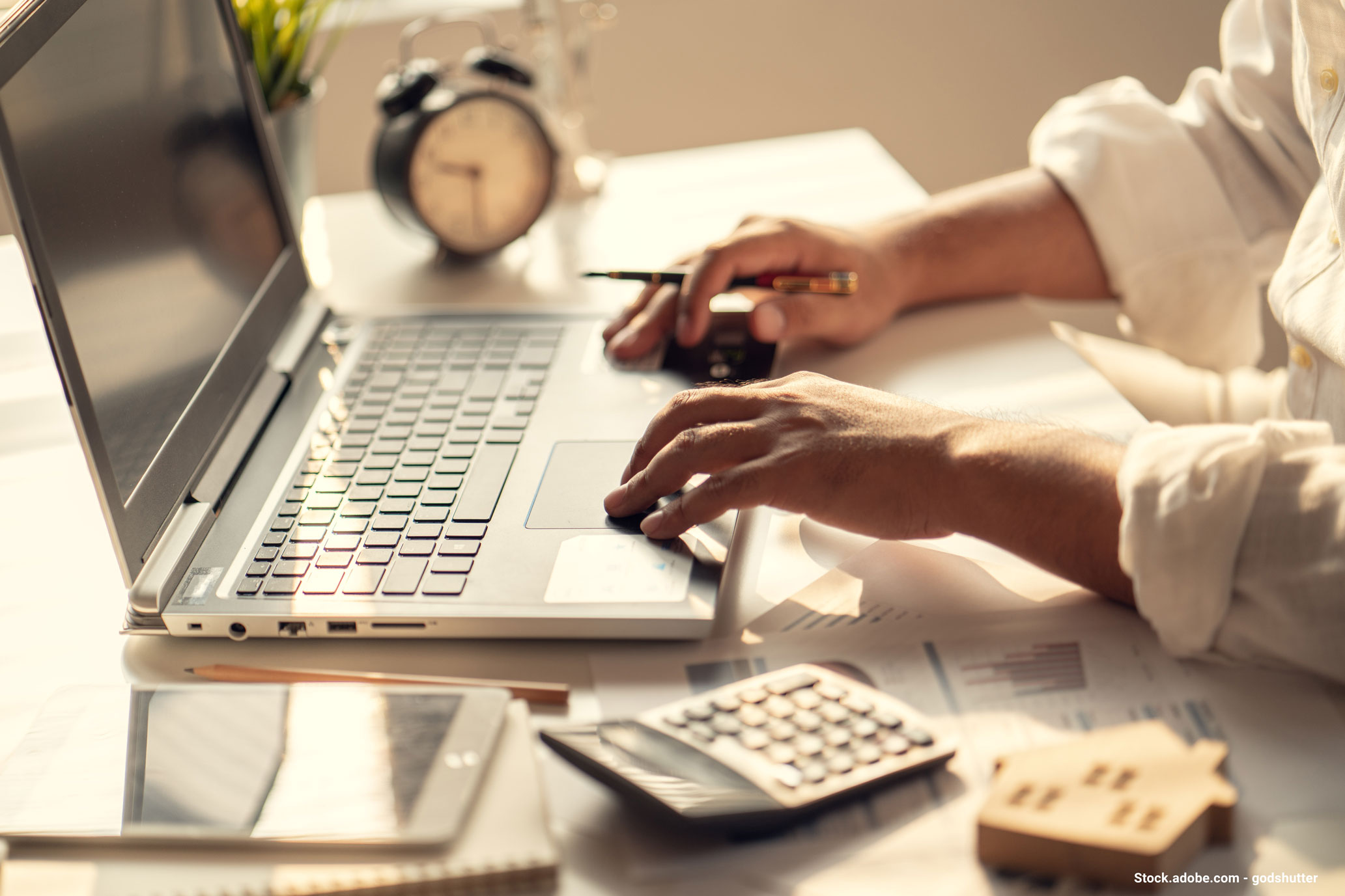 Une personne devant un ordinateur fait les comptes avec une calculette et des tickets de caisse pour symboliser l'endettement
