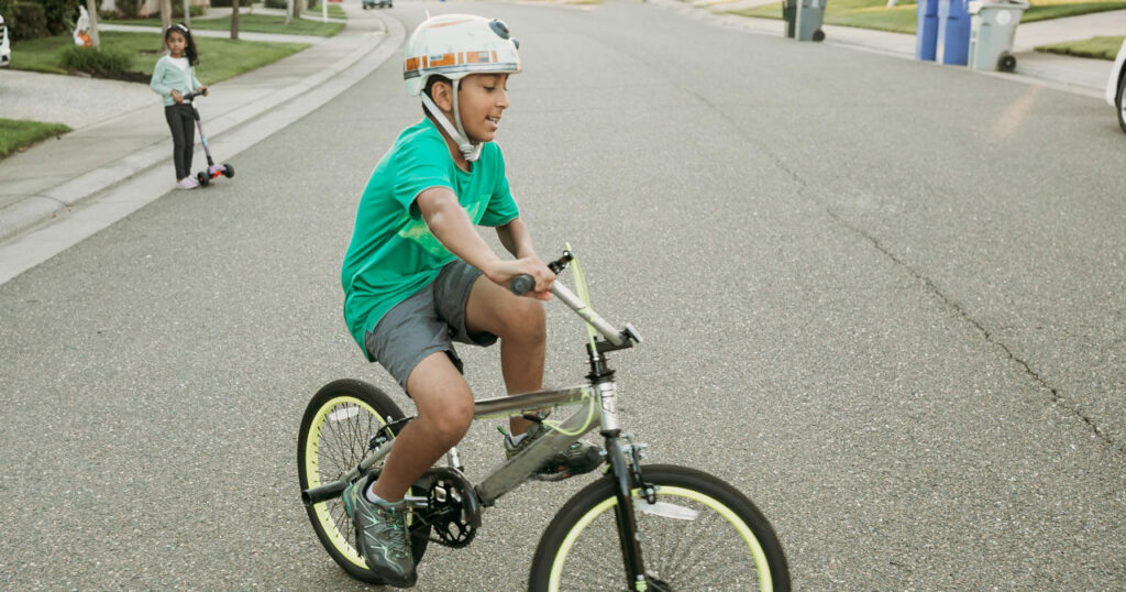 Un enfant fait du vélo sur une route et porte un casque