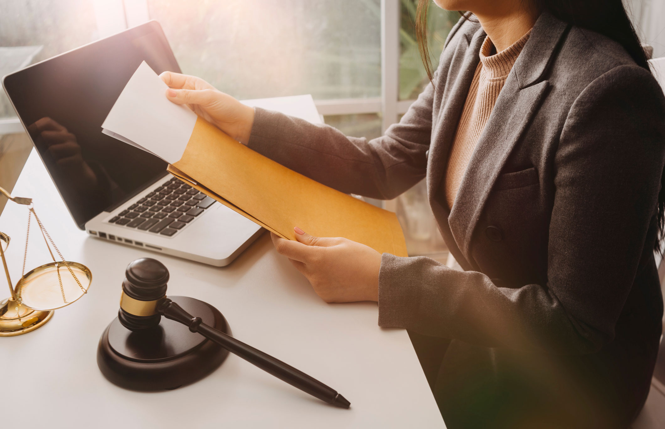 Illustration d'un huissier de justice avec une femme à son bureau sur lequel sont posés un marteau, une balance et un ordinateur