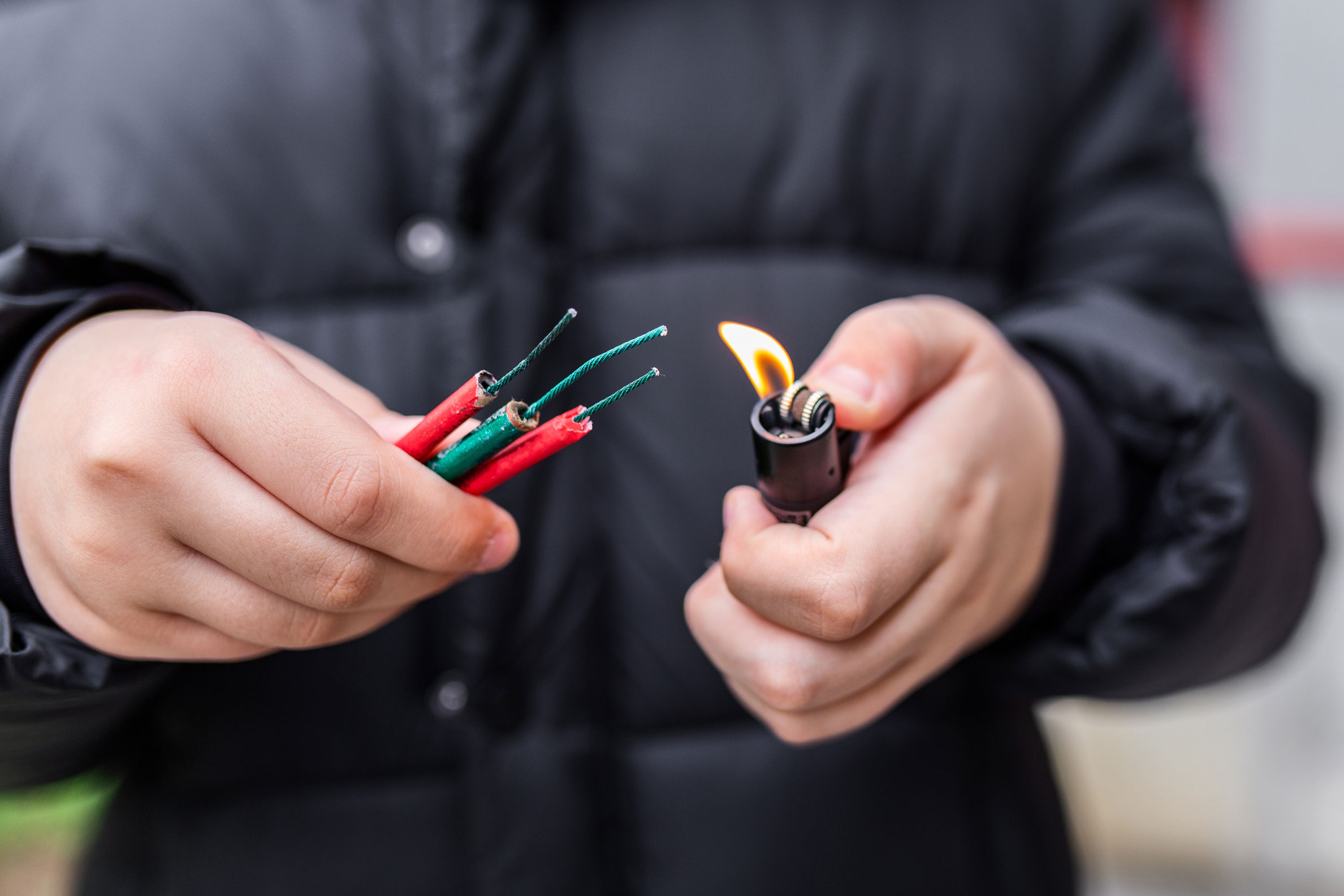 Une personne tient des pétards dans sa main droite et un briquet dans la main gauche.