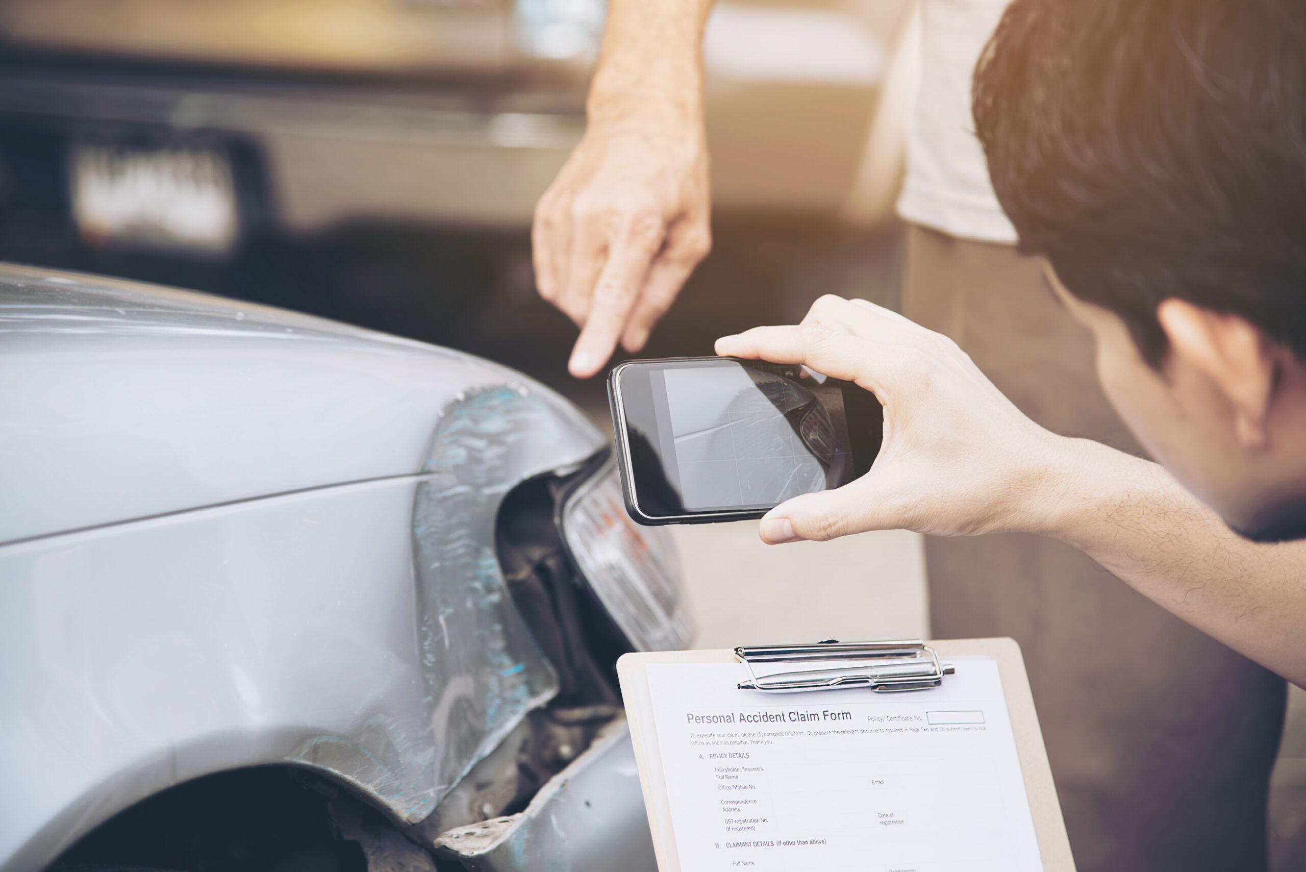 Un automobiliste prend une photo des dégâts de l'accident de voiture en même temps qu'il remplit le constat amiable
