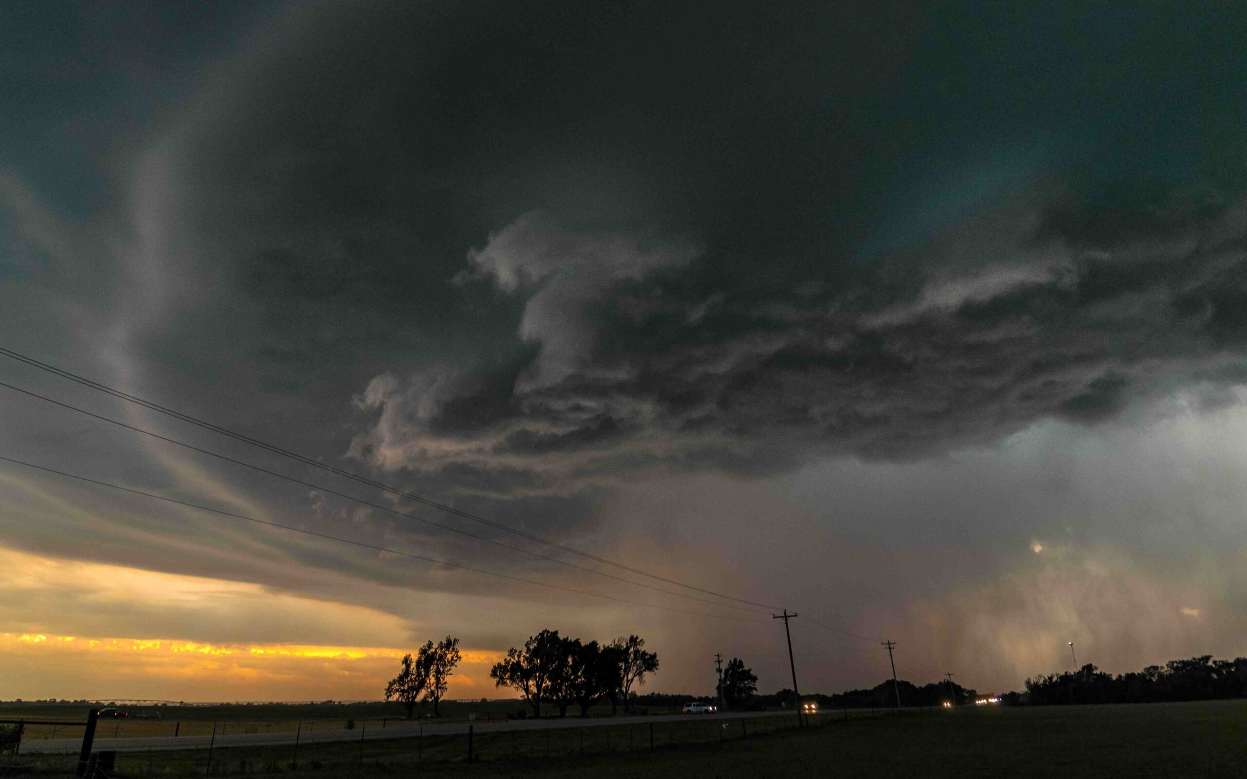 Dunkle Gewitterwolken hängen über einer flachen Landschaft.