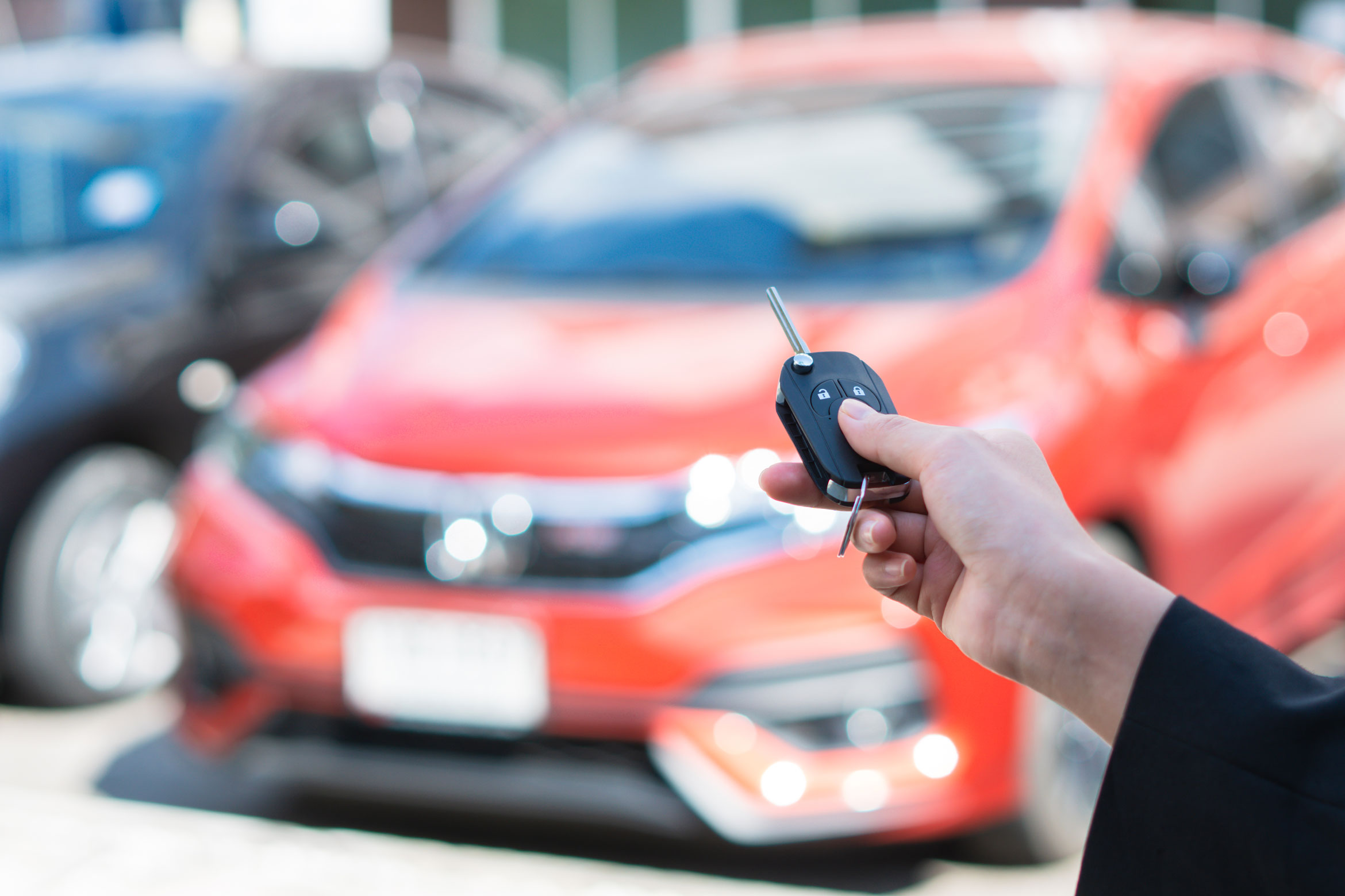 Une personne tient dans sa main la clé d'une voiture et la pointe vers le véhicule