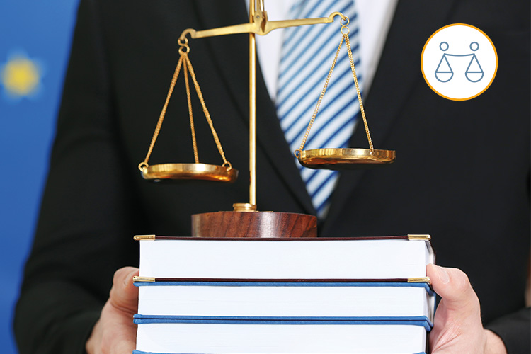 Une balance représentant la justice est posée sur trois livres tenus par une personne