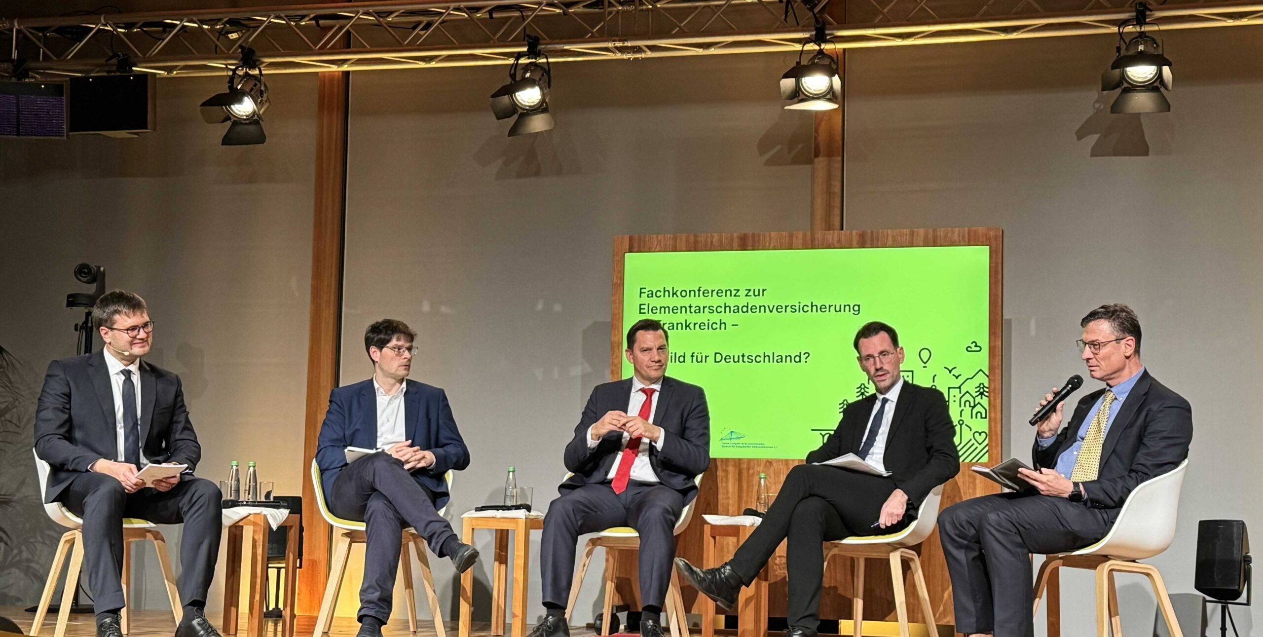 Jakob Thevis moderiert den Austausch am runden Tisch bei der Konferenz zur französischen Elementarschadenversicherung in Berlin.