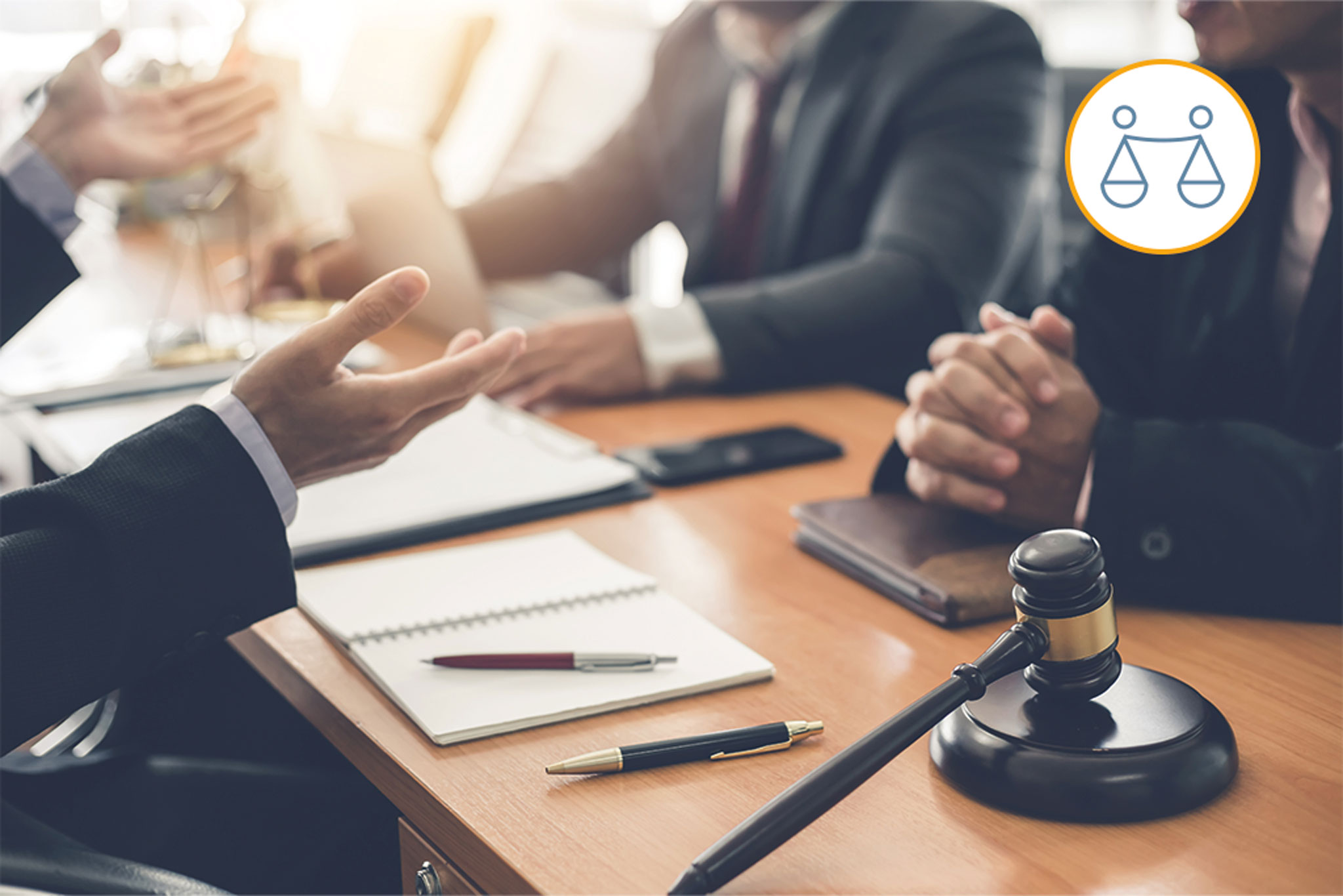 Personen sitzen an einem Tisch. Nur die Hände sowie Unterlagen und ein Laptop sind zu sehen. Eine Person scheint beim Spreche zu gestikulieren.