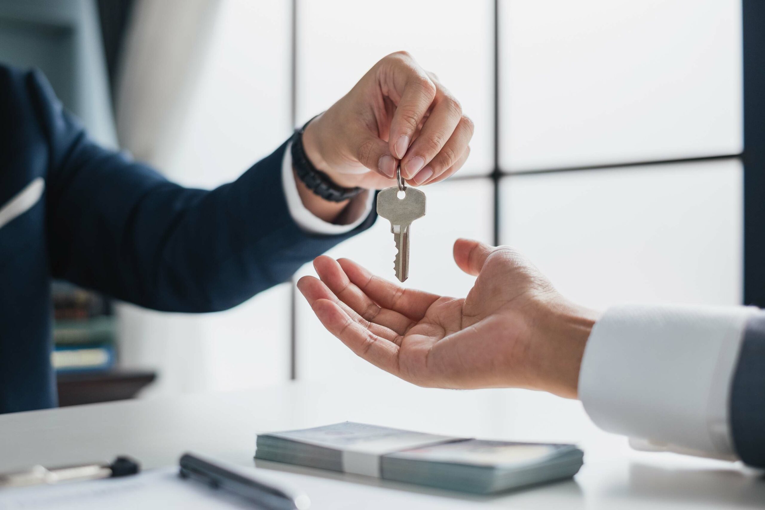 Ein Immobilienmakler übergibt einer Person einen Wohnungsschlüssel.