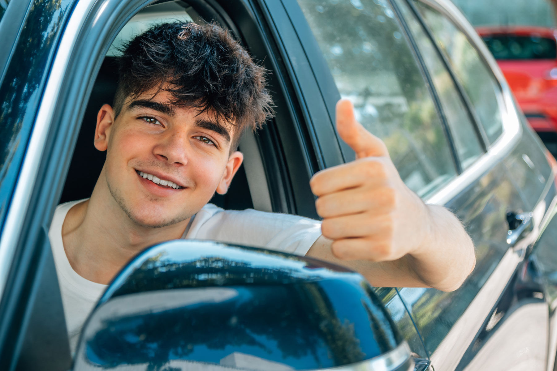 Un jeune de 17 ans souriant a son permis de conduire et peut prendre le volant tout seul