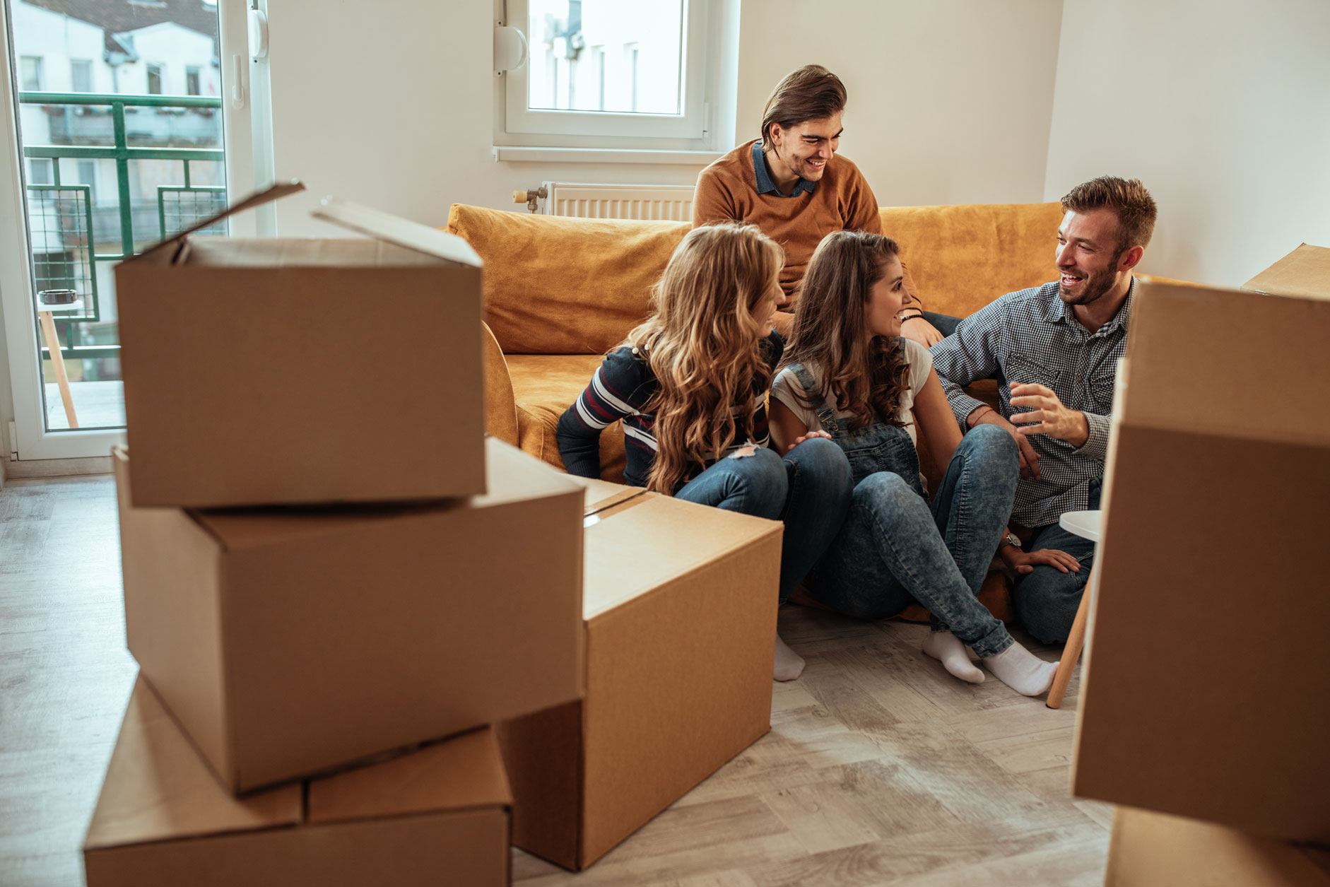 Quatre jeunes qui emménagent ensemble dans une colocation sont assis dans le salon avant de finir de déballer les cartons
