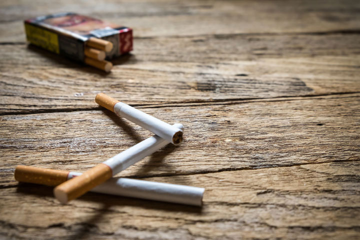 Achat de tabac transfrontalier : des cigarettes et un paquet posés sur une table en bois.