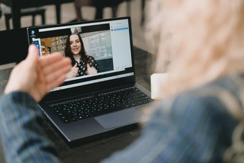 Eine Frau sitzt vor einem Laptop und nimmt an einer Online-Konferenz teil.