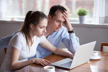 Ein Paar ist Opfer eines Online-Betrugs geworden. Beide schauen verzweifelt auf den Bildschirm ihres Laptops.