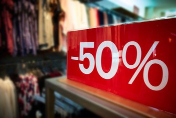 Gros plan sur une pancarte de soldes indiquant "-50%" dans une boutique de vêtements.