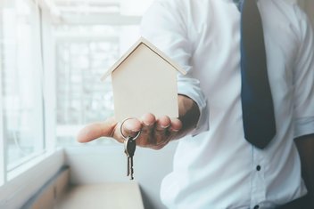 Ein Immobilienmakler hält einen Schlüssel in der Hand.