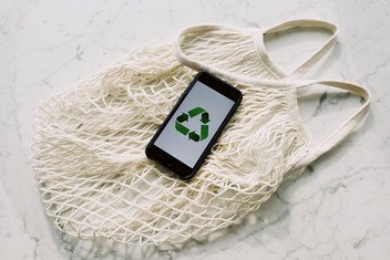Un smartphone affichant un logo de recyclage avec un sac réutilisable en dessous