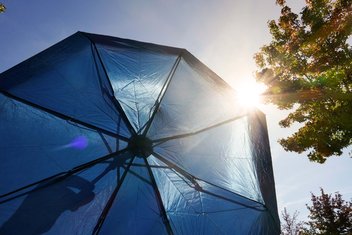 Vue du bas d'un parapluie qui protège des rayons du soleil.